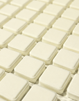A close-up view of multiple small square off-white plastic or rubber pads arranged in rows on a tray or surface.