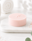Pink soap bar on a white marble stand with eucalyptus leaves in the background