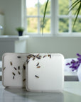 Two white shower steamers with lavender buds on a marble surface in a bathroom setting.