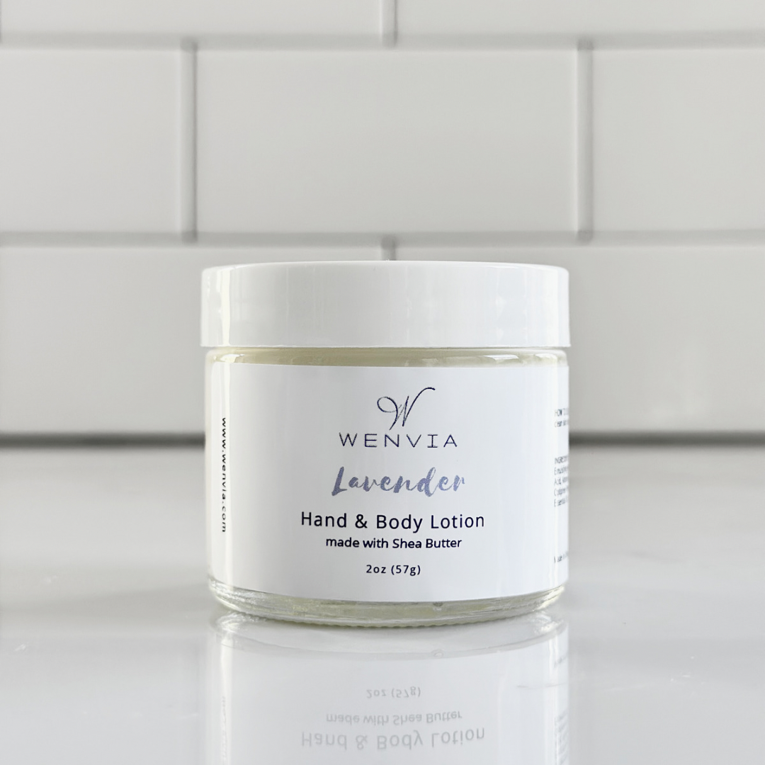A jar of WENVIA Hand & Body Lotion with a label that reads 'Lavender' and 'made with Shea Butter'. The jar is placed against a tiled wall.