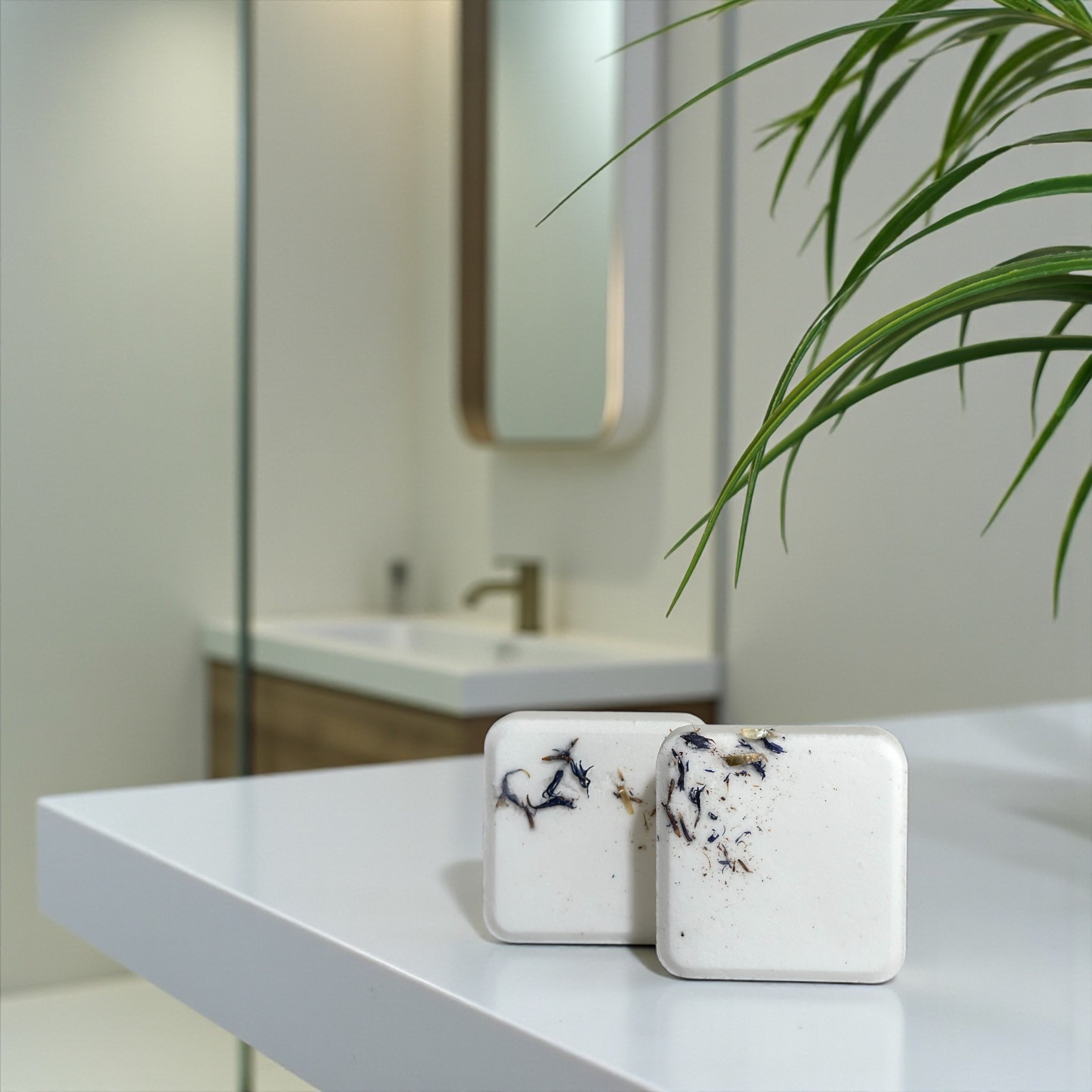 Two decorative shower steamers on a white surface with a blurred bathroom background